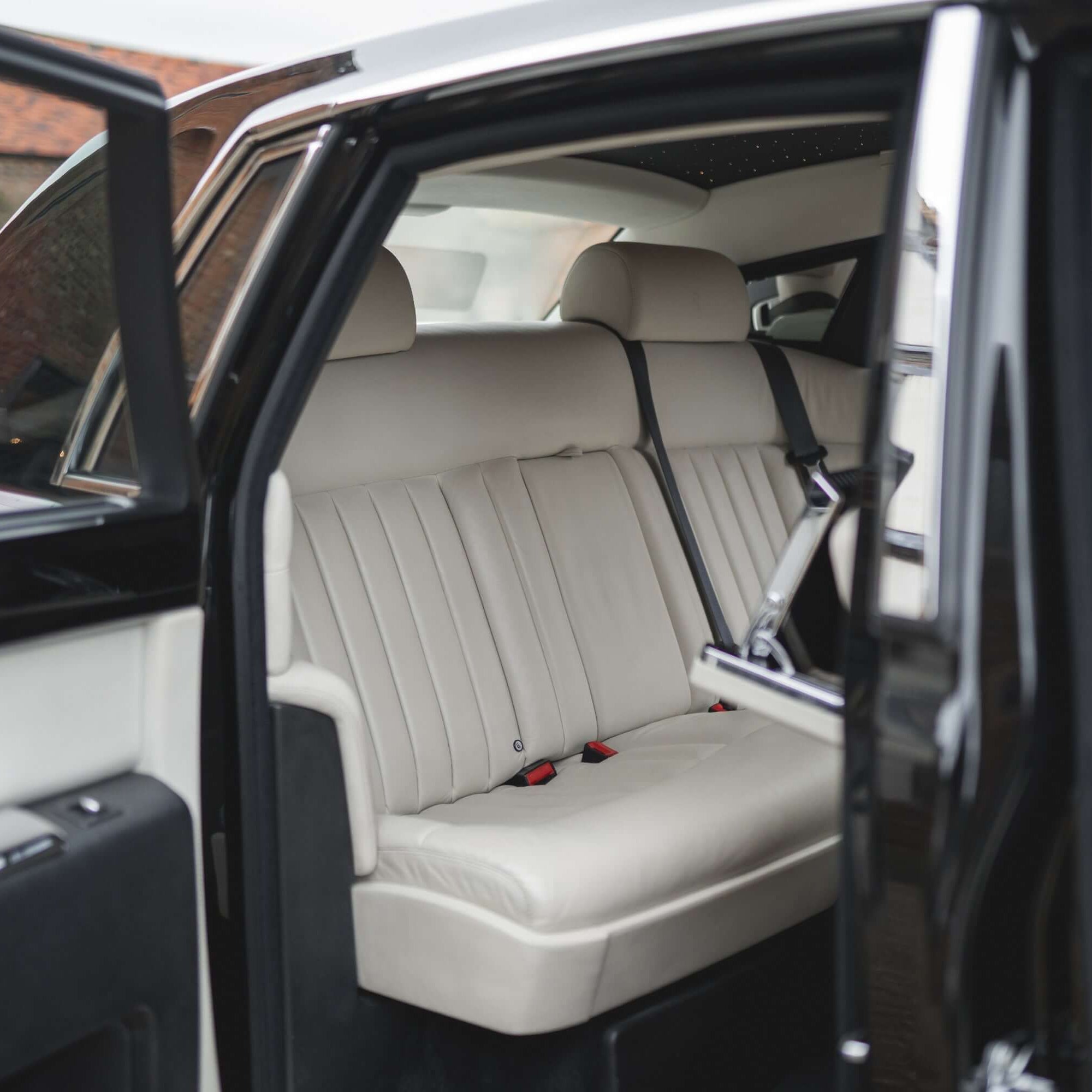SJ Chauffeurs: Luxurious Rolls Royce rear cabin with open doors, inviting passengers for premium travel