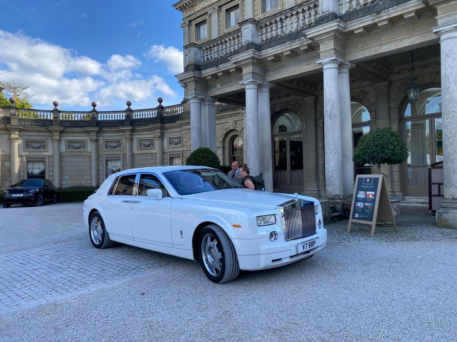 Elegant white Rolls-Royce Phantom parked outside a luxury wedding venue. Experience premium wedding chauffeur services with SJ Chauffeurs, offering luxury car hire for weddings, VIP events, and executive travel across the UK. Book your chauffeur-driven Rolls-Royce today